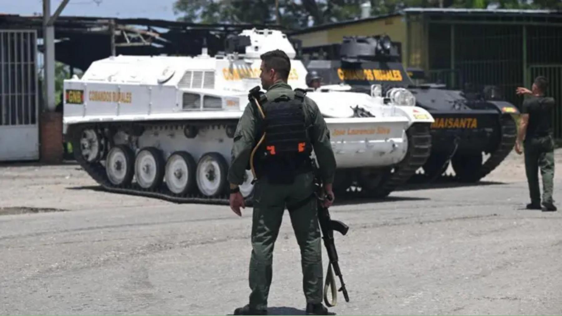 Miembros de la Guardia Nacional Bolivariana (GNB) se sientan en un vehículo blindado frente a la prisión de Tocorón en Tocorón, estado Aragua, Venezuela